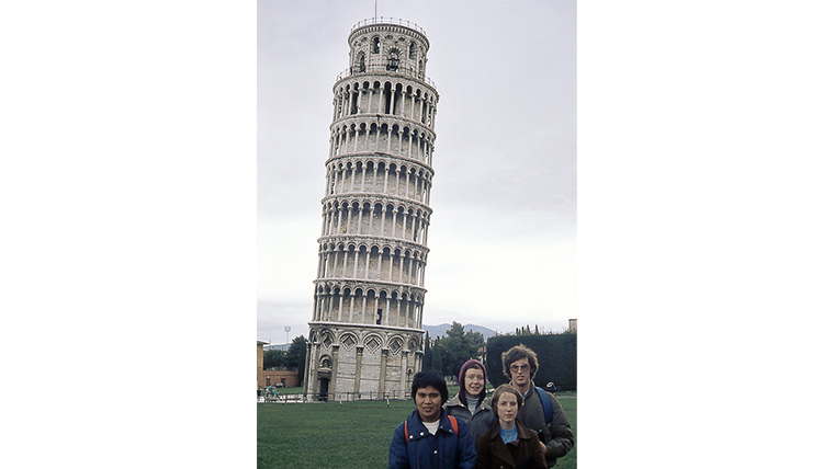 A group of four students shares a photo in front of the Leaning Tower of Pisa.