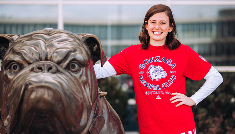young woman in Kennel tshirt next to bronze bulldog at GU