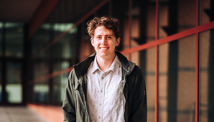 young man in jacket outside foley library building