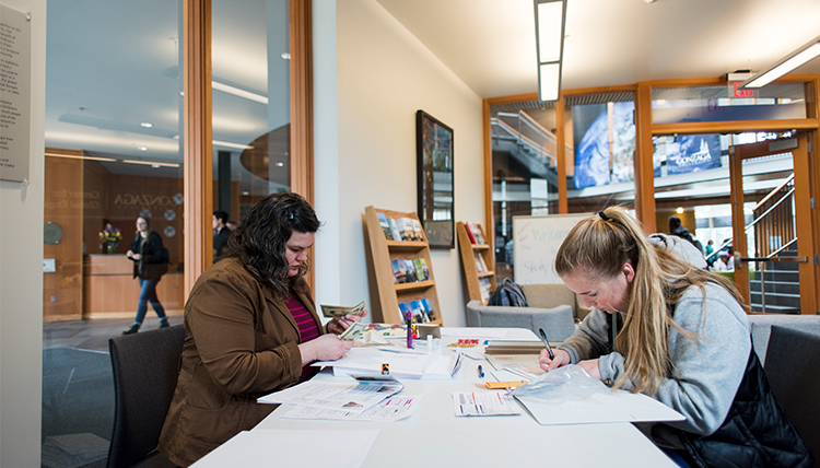 A student works with a study abroad staff member to fill out forms for their visa. 