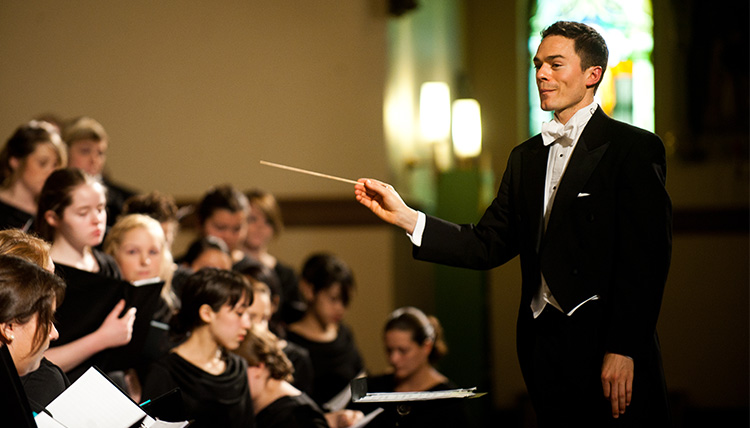 The choir director leads a group of singers.