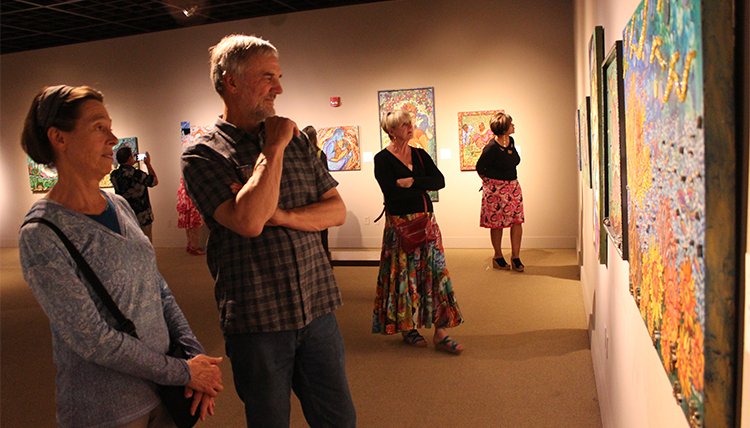 A man and a woman gaze at a painting in a gallery in a museum.