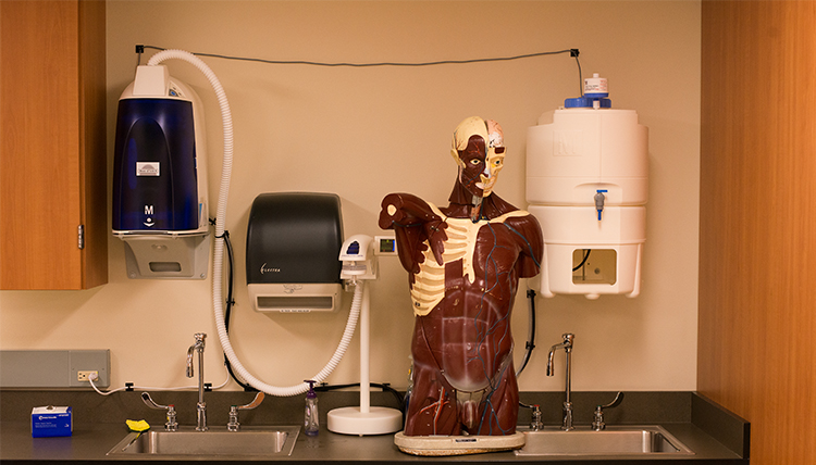 Materials for a nursing lab are shown, including some medications, a human body mannequin, and a wash station.