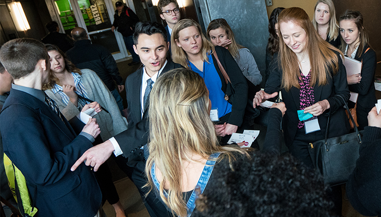 A group of students and professionals network and chat during a career trek.
