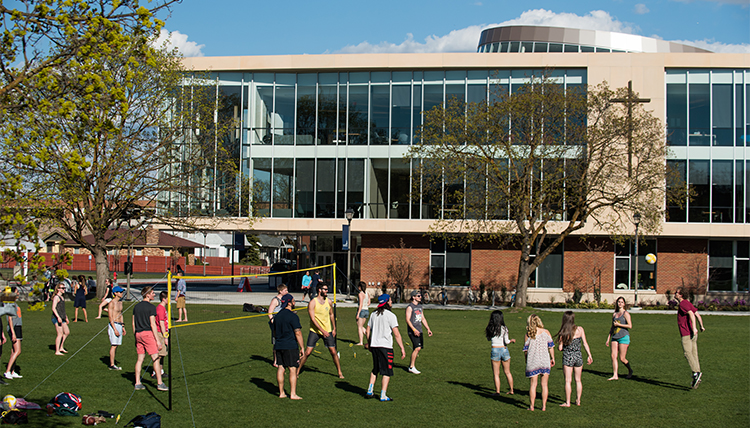 A group of students plays pickup volleyball on the quad on campus on a spring afternoon.