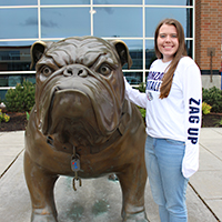 Emily Arnesen stands next to Spike the Bulldog.