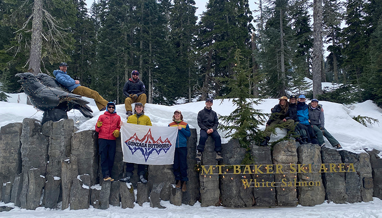 group poses with Mt Baker sign and GU Outdoors flag