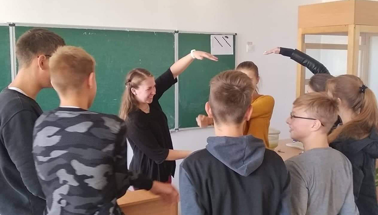 Woman in a classroom smiling as she works with a group of students