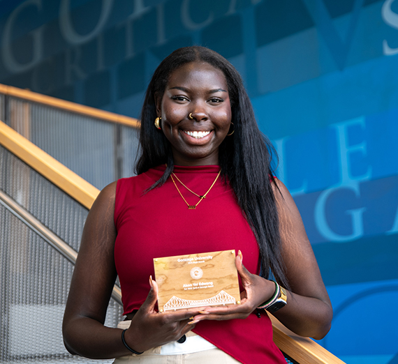 Akon Edwang smiling and holding the Sue Weitz Spirit of Gonzaga Award at Gonzaga University's Magis Awards.