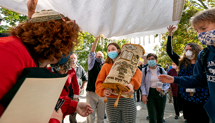 student carries the Torah under protection