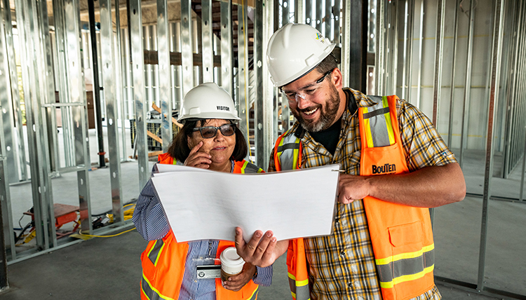 provost and construction person review blueprints in facility under construction