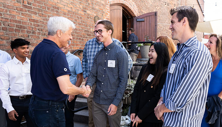 JPMorgan Chase CEO Jamie Dimon and Gonzaga student Kaden McCullough shake hands while other GU students stand nearby