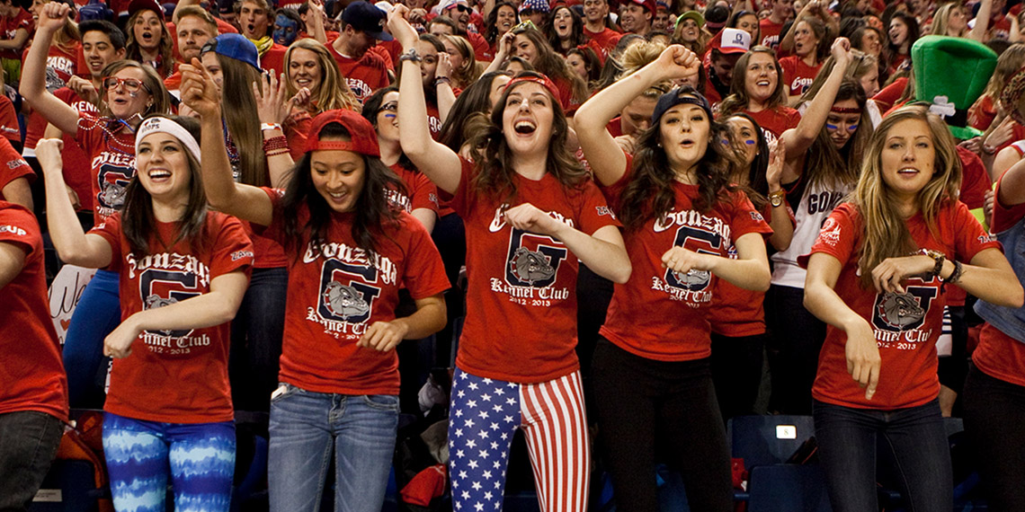 Students cheering in Gonzaga's Kennel Club section at a basketball game