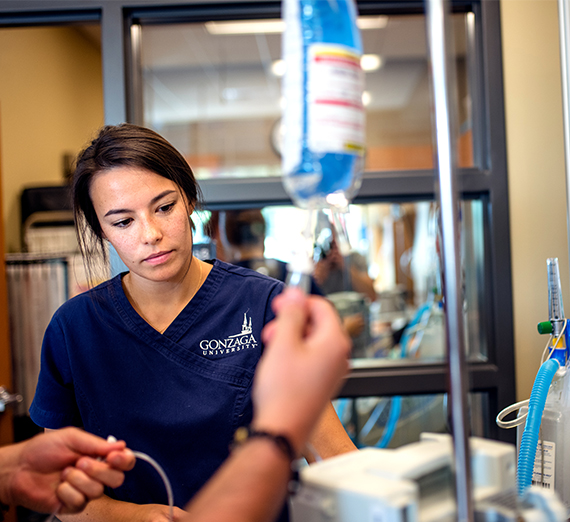 A nursing student checks information while using an IV during a simulation lab. 