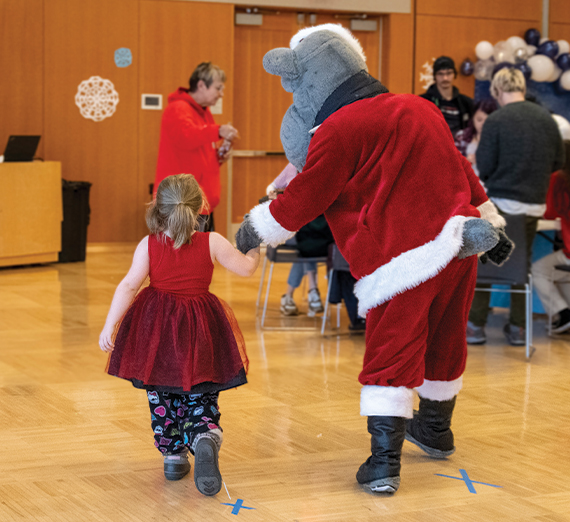 Gonzaga Mascot Spike, wear a Santa outfit holding the hand of a little girl during the Winter Wonderland event.  