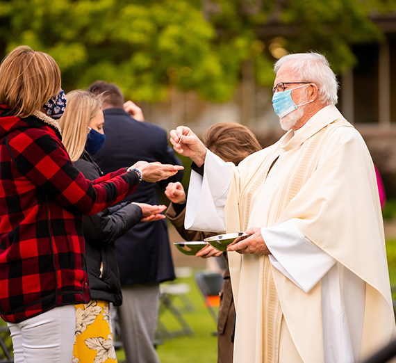 Priest offers communion at outdoor Mass
