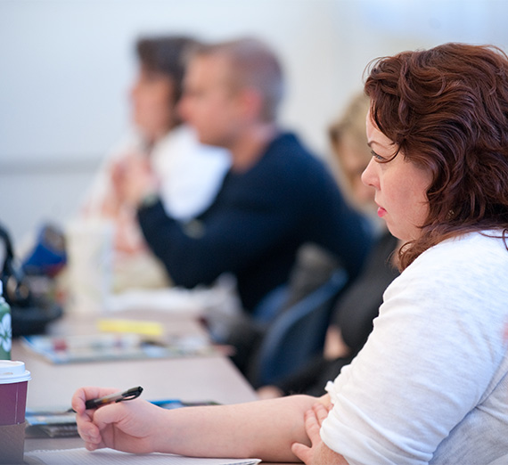 A woman takes notes in a classroom.