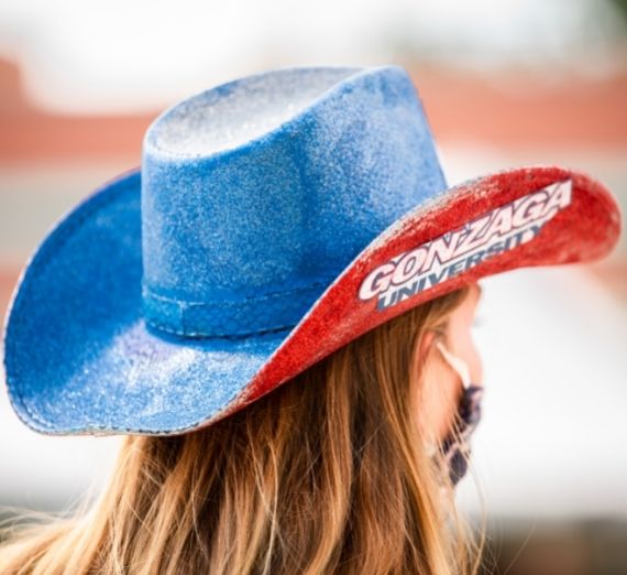 A photo of a student where a Gonzaga-themed cowboy hat. Only the back of the hat is seen. It is red and blue with the Gonzaga logo on it.