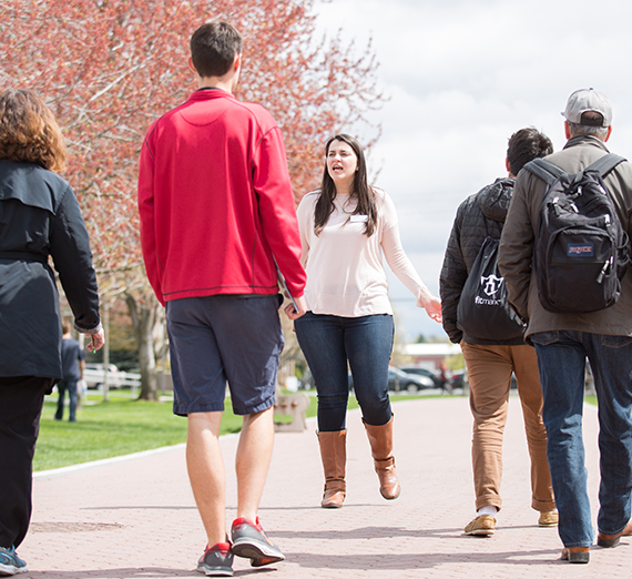 A student tour guide shows the campus around to a group of visitors in the spring.