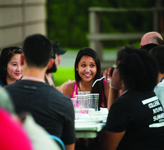 Students sit laughing at a round table.