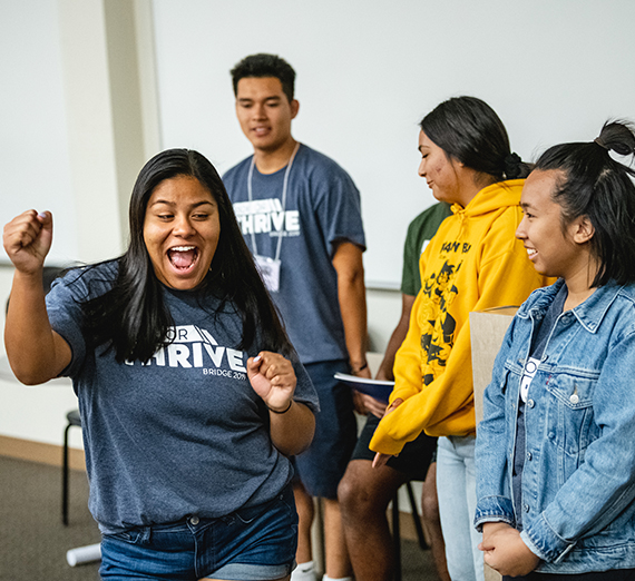 One student dances while another watches; both are laughing.