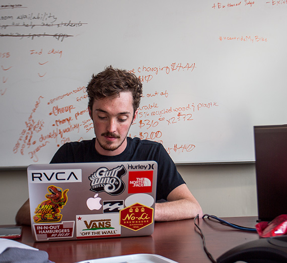 A student sits in a study room and works on a computer.