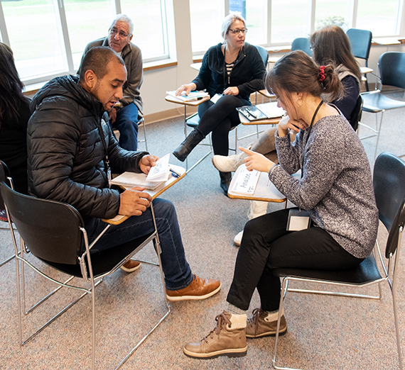 A tutor works with an English learning student in a classroom.