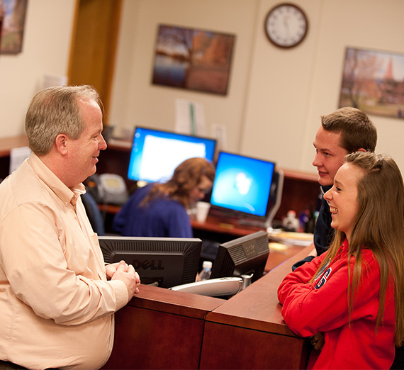 A financial aid staff members talks to students in the office. 