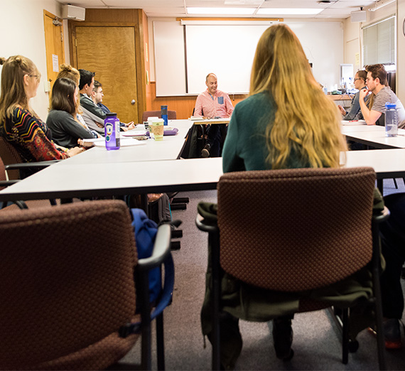 Students engage in a round table discussion in a classroom.