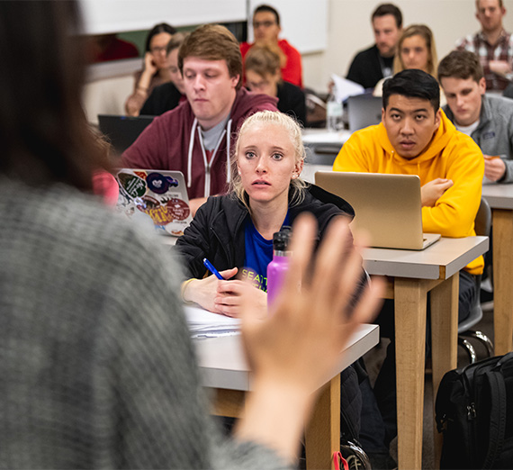 A professor lectures to a group of students in a classroom