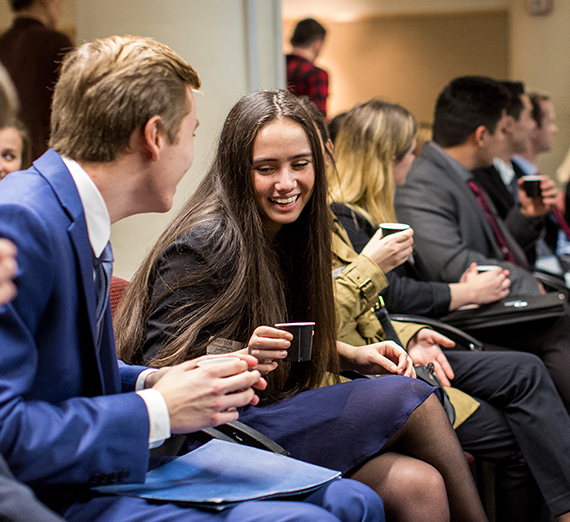 Students sit in business attire at a presentation on a career trek.