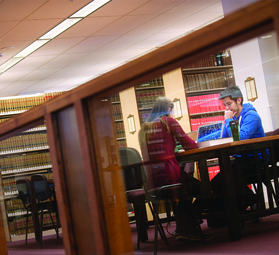 Two students sit and study at a table in the library.