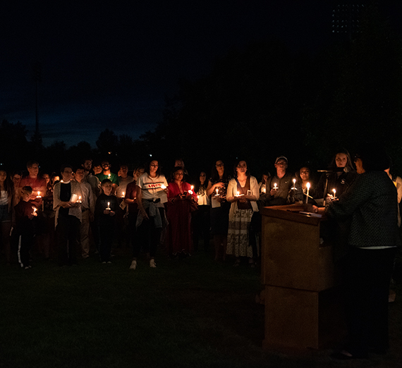 Students, faculty and staff link arms in a candlelit ceremony standing in support of undocumented people. 