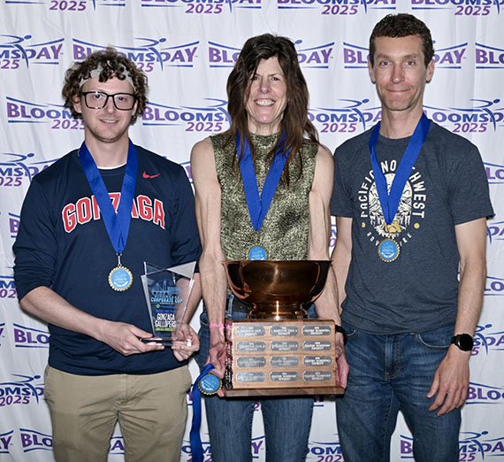 Jackie Van Allen, Richard Keroack, and Chris Fink pose with medals and trophies after Gonzaga’s 2025 Bloomsday Corporate Cup win.