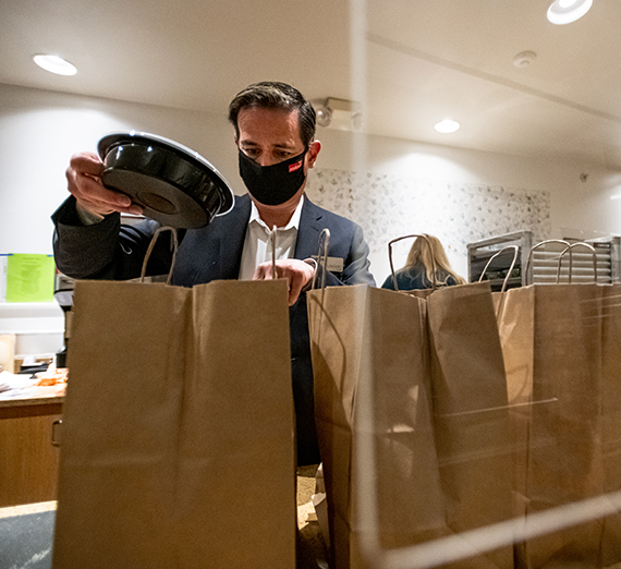 Man putting food into a brown paper bag 