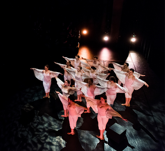 group of dancers on a dark stage