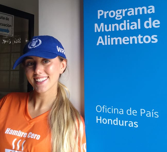 Erin Bergmann posing in front of sign that says "World Food Program" and "Country Office of Honduras"