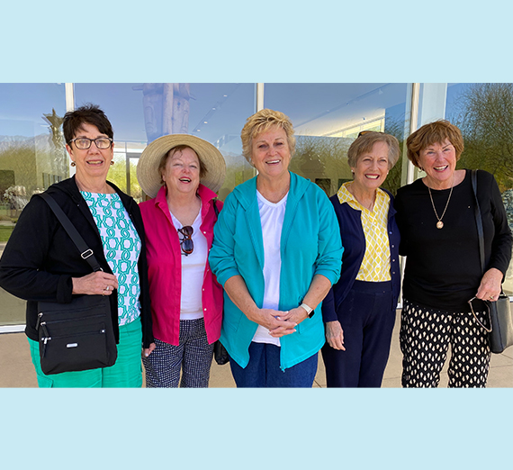 Five women pose together. 