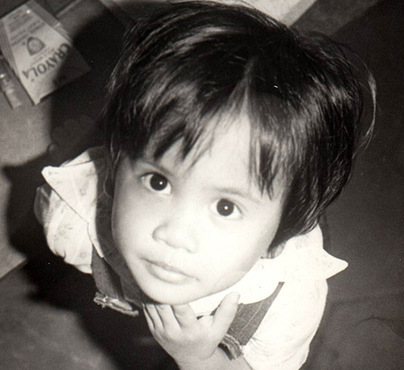 Child in black and white looking up at camera.