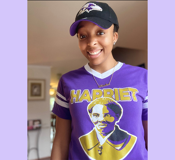 young black woman in purple shirt with photo of Harriet Tubman 