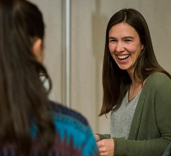 One female student smiles at another, perhaps in mid-conversation