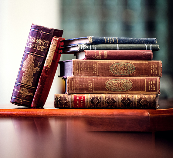 A stack of rare books, covers slightly worn and faded, piled on a table in Foley Library.
