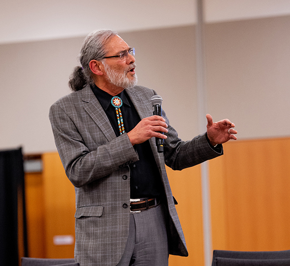 man gestures while talking into microphone