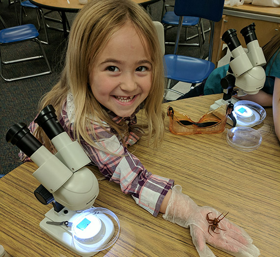 Female elementary student holding a spider 