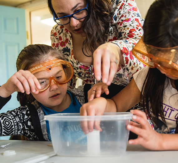 Two youth conduct an experiment with their instructor.