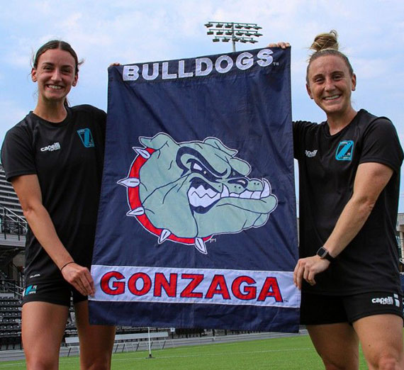 Sophia Braun (’22) and Jodi Ülkekul (’18) holding a Gonzaga Bulldogs banner.