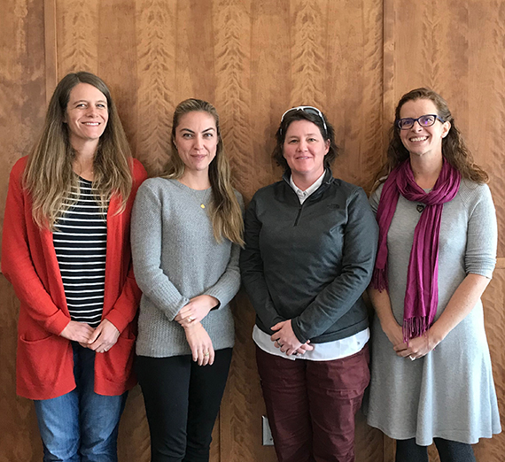 Four female faculty standing and smiling together