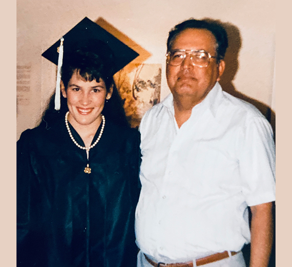 female college grad in cap and gown with father