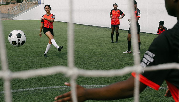 A girl kicks a soccer ball towards a goal