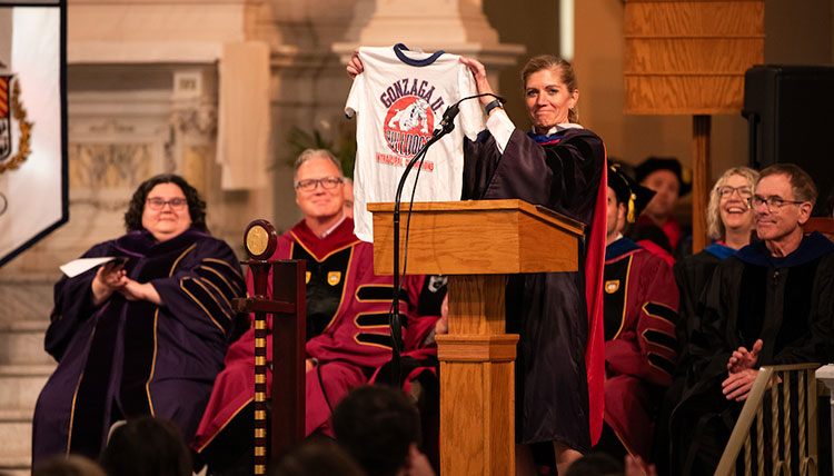 Interim Provist Mia Bertagnolli holds up a Gonzaga t-shirt as several faculty members look on